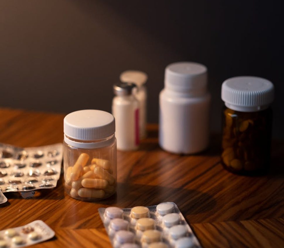 Various pills and medicine bottles on a wooden table, ideal for healthcare themes.